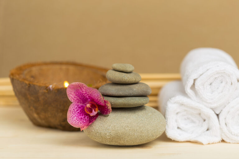 Spa-inspired setting with massage stones, essential oil and towels representing relaxation and wellness