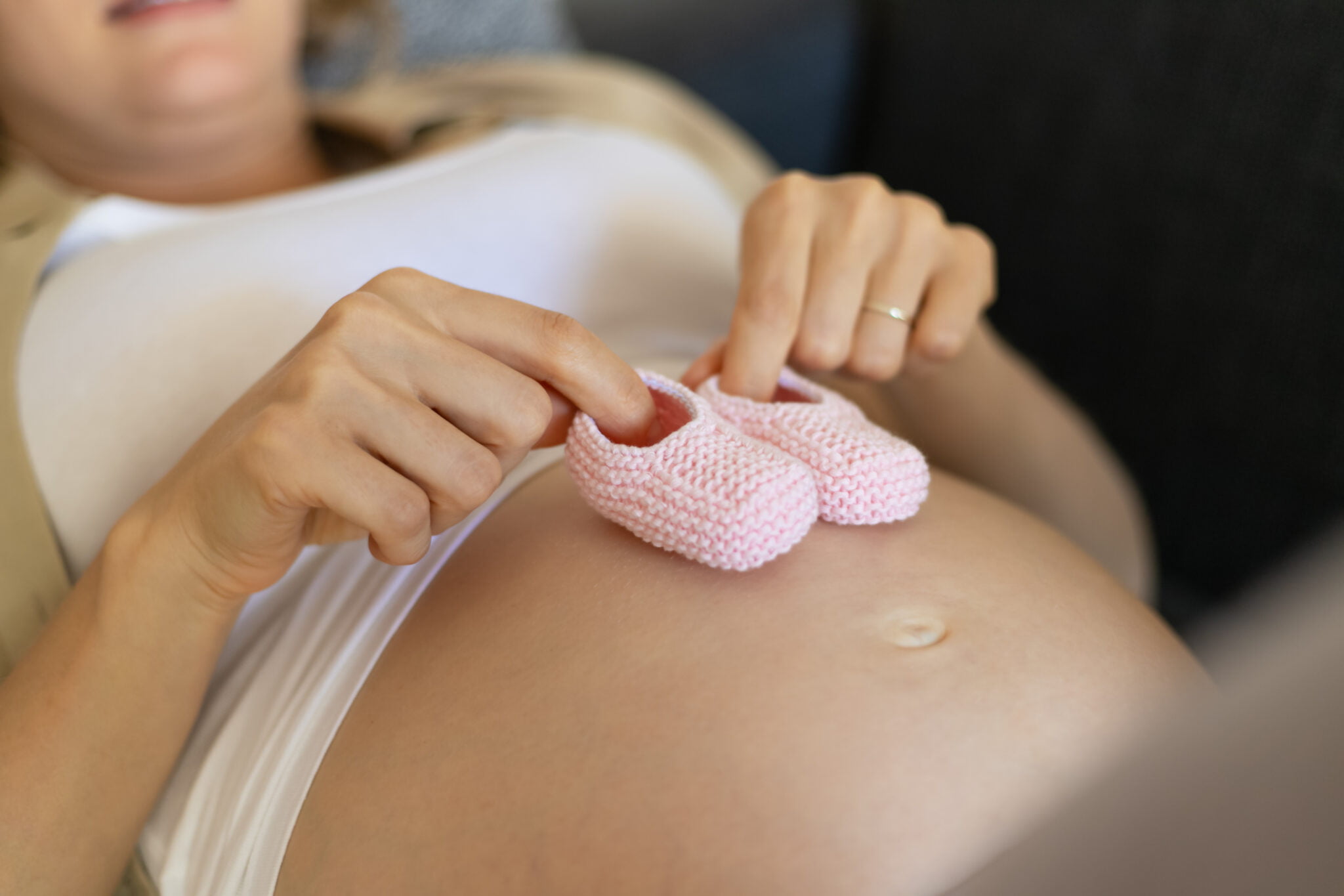 Expecting mother resting with baby shoes during pregnancy in Edmonton