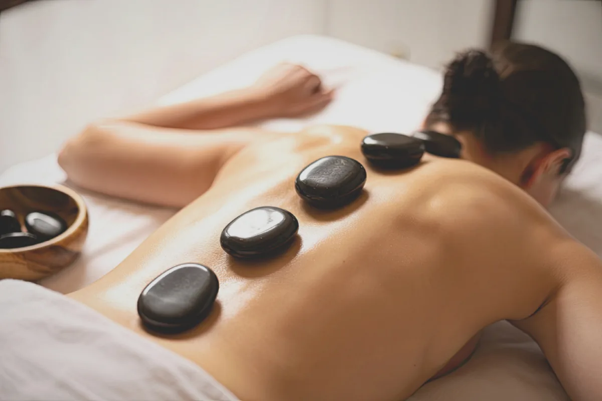 Hot basalt stones placed along client's back during massage in Edmonton