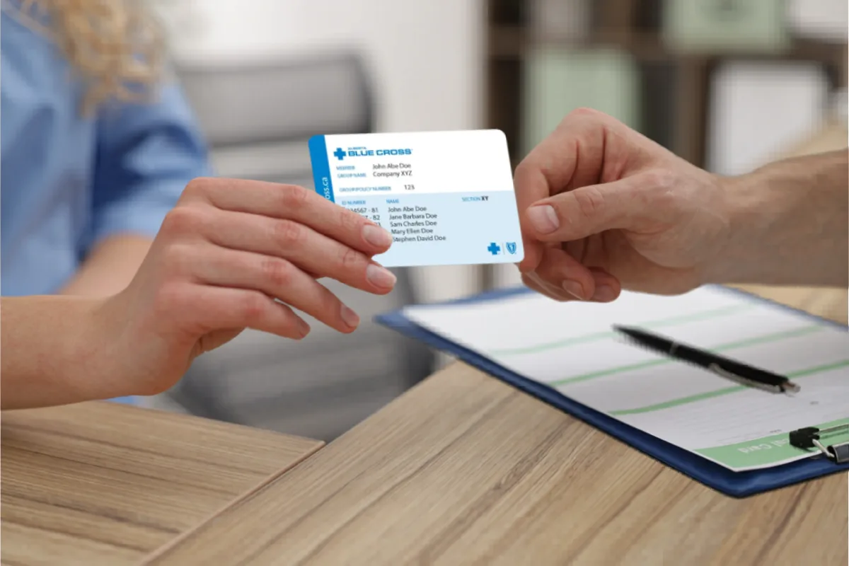 Client handing Alberta Blue Cross insurance card at massage therapy clinic in Edmonton