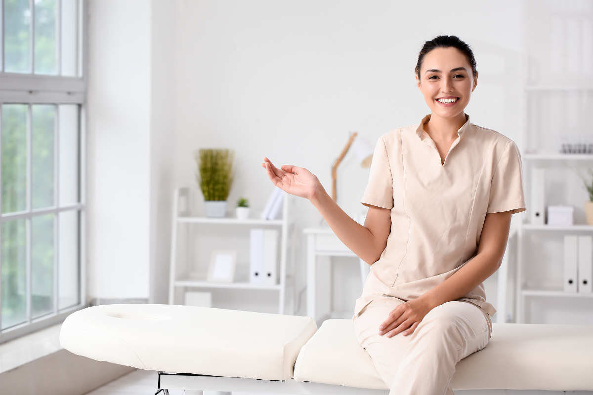 Friendly registered massage therapist sitting on treatment table at massage clinic in Edmonton