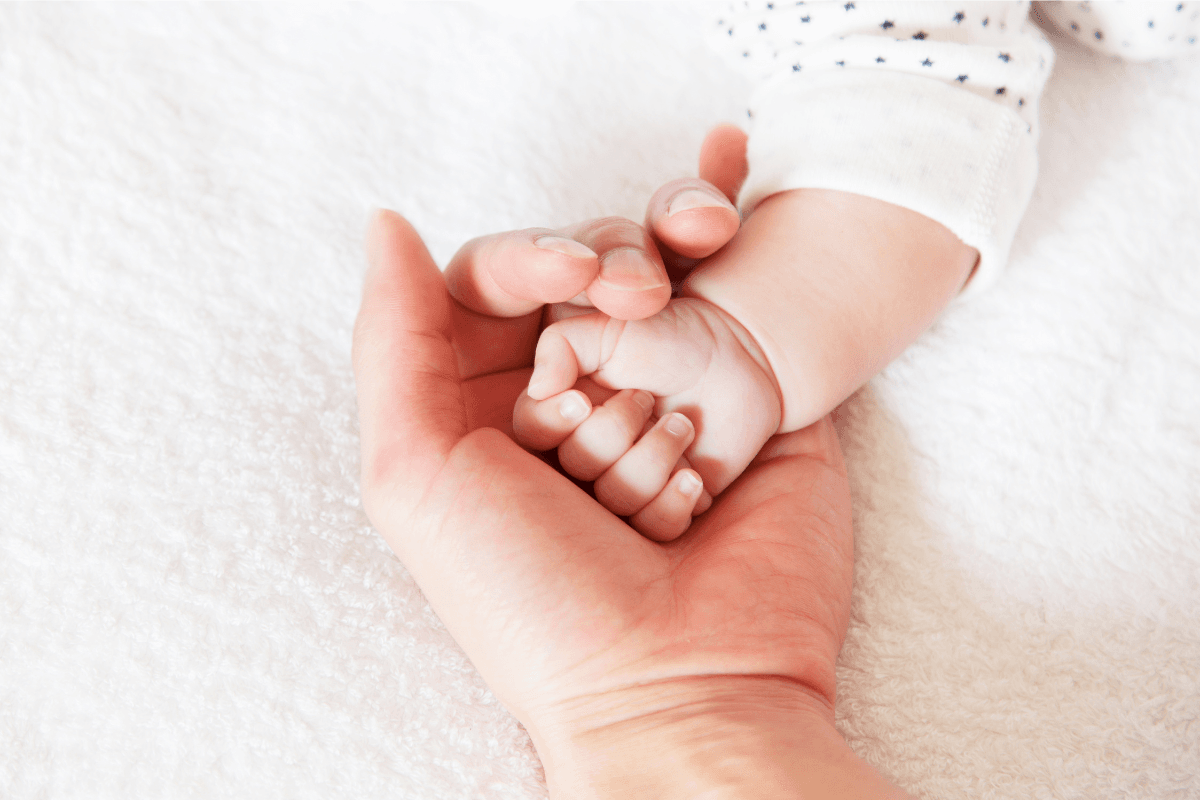 Adult hand gently holding newborn baby hand representing prenatal care in Edmonton